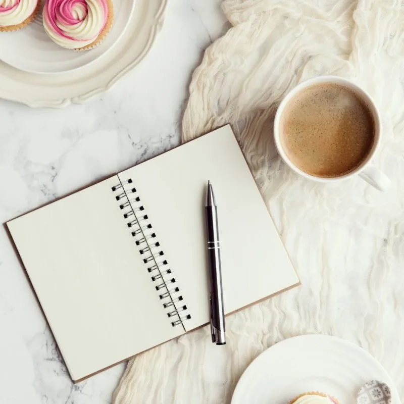 journal with pen and coffee on bed