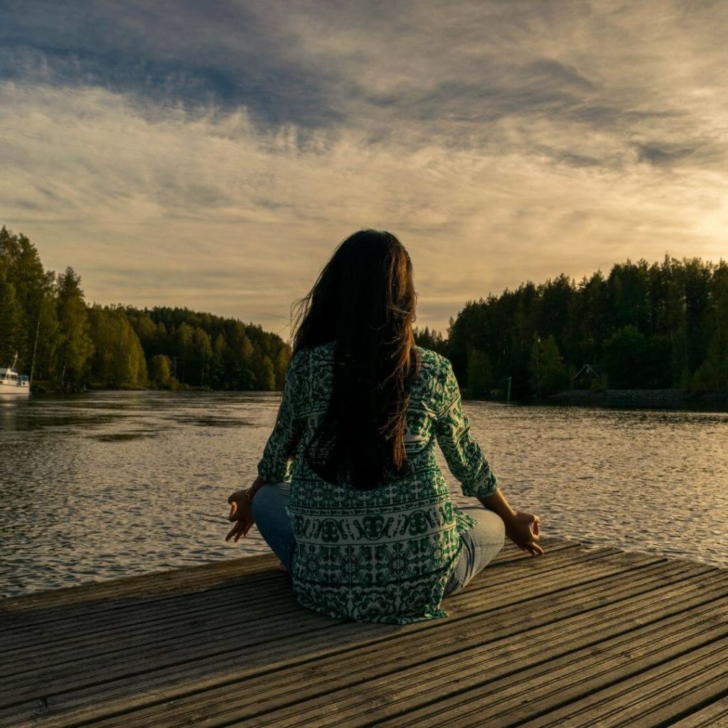 Girl meditating by lake