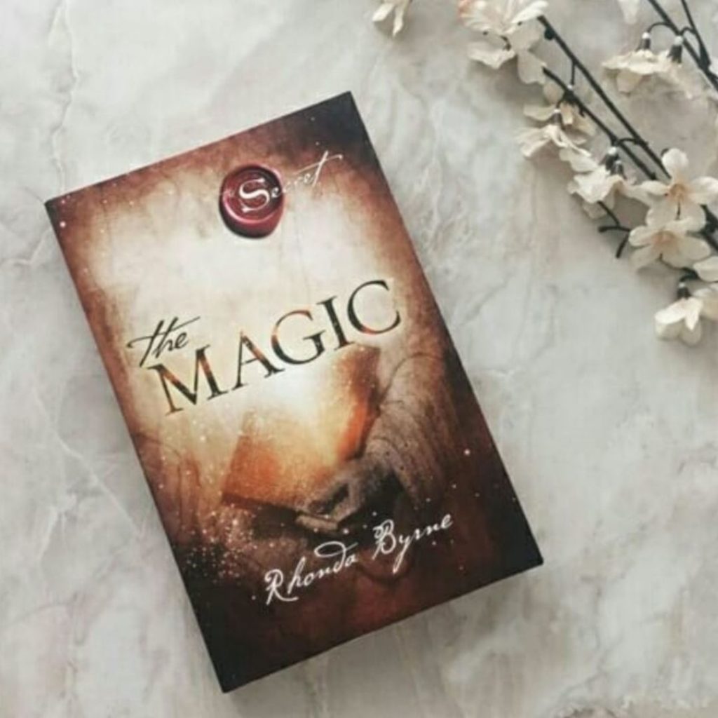 the magic by rhonda byrne on marble next to flowers